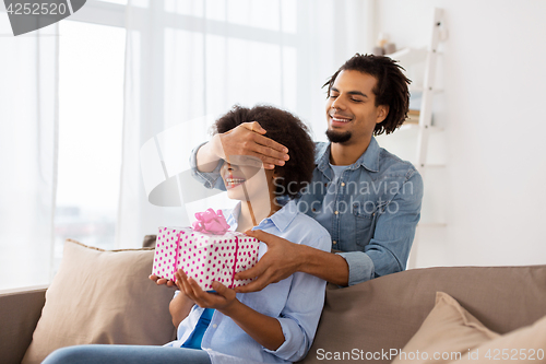 Image of happy couple with gift box at home