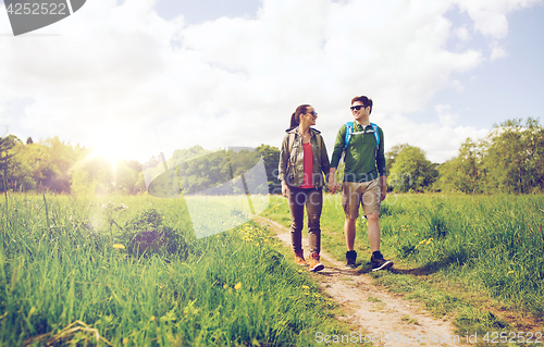 Image of happy couple with backpacks hiking outdoors