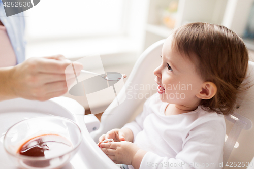 Image of mother feeding baby with puree at home