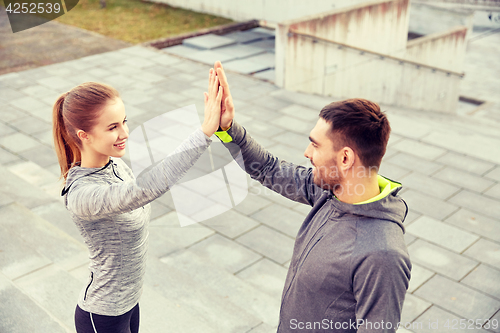 Image of smiling couple making high five on city street