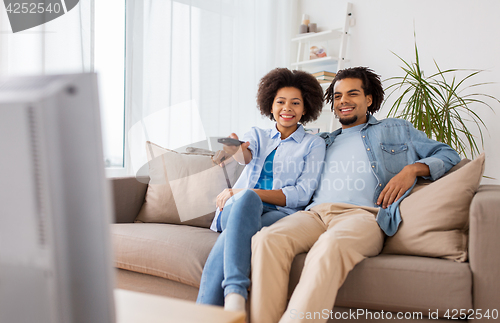 Image of smiling couple with remote watching tv at home