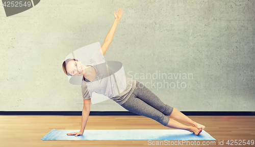 Image of woman making yoga in side plank pose on mat