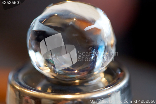 Image of hand-cut ice ball on top of cocktail shaker at bar