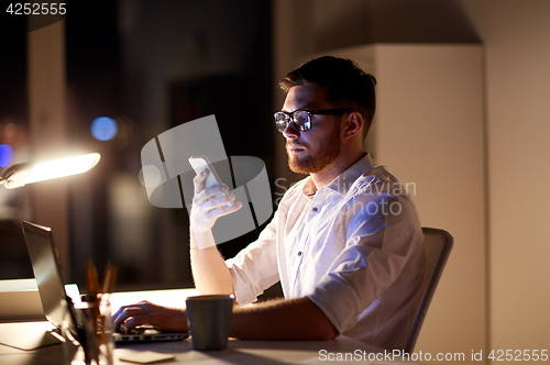 Image of businessman texting on smartphone at night office