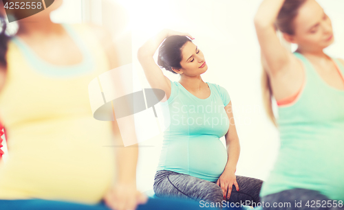 Image of happy pregnant women exercising on fitball in gym