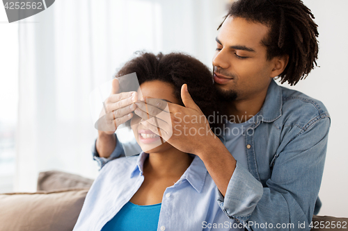 Image of happy man closing woman eyes at home