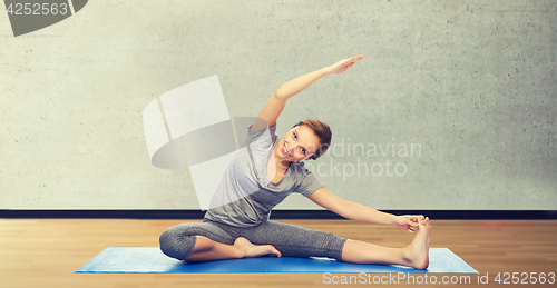 Image of happy woman making yoga and stretching on mat