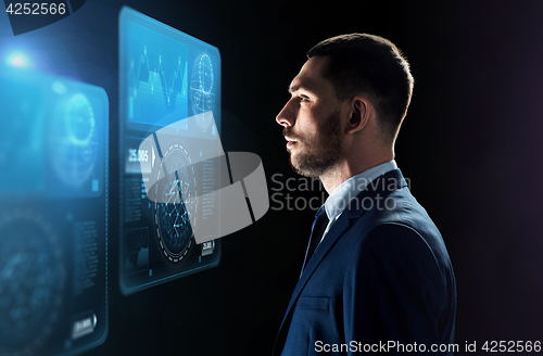 Image of businessman looking at virtual screens over black