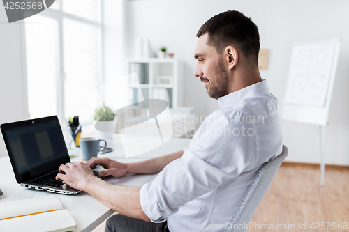 Image of businessman typing on laptop at office