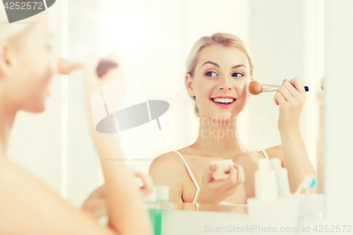 Image of woman with makeup brush and powder at bathroom