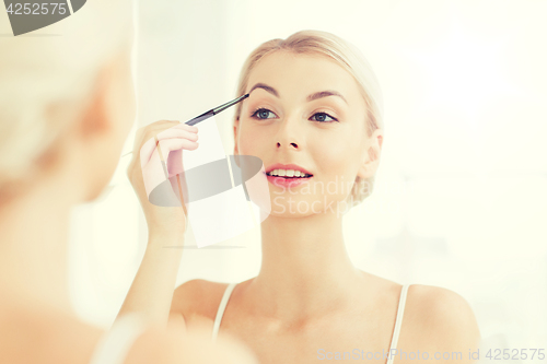 Image of woman with brush doing eyebrow makeup at bathroom