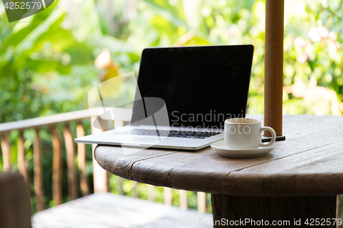 Image of coffee cup and laptop computer on table outdoors