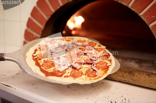 Image of peel placing pizza into oven at pizzeria