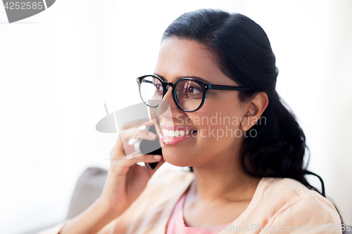 Image of happy indian woman calling on smartphone at home