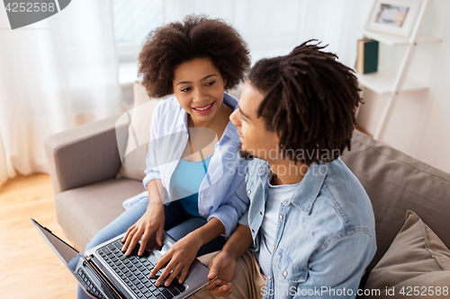 Image of smiling happy couple with laptop at home