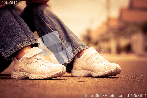 Image of youth sneakers on girl legs on road