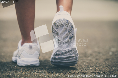 Image of youth sneakers on girl legs on road