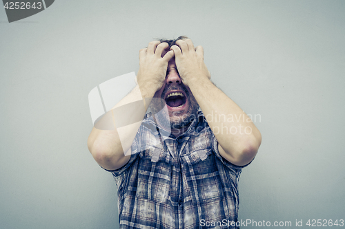 Image of portrait one sad man standing near a wall and covers his face