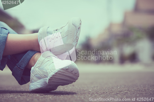 Image of youth sneakers on girl legs on road
