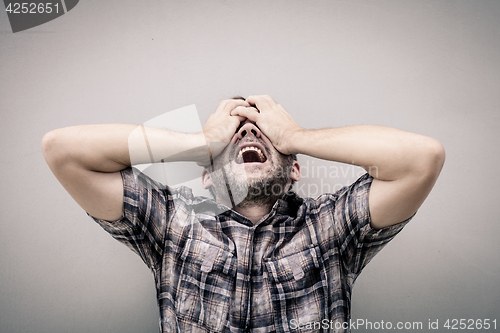 Image of portrait one sad man standing near a wall and covers his face