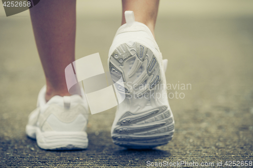 Image of youth sneakers on girl legs on road