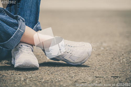 Image of youth sneakers on girl legs on road