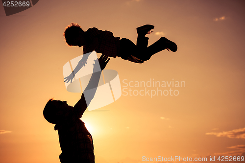 Image of Father and son playing on the beach at the sunset time.