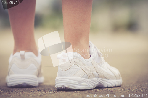 Image of youth sneakers on girl legs on road