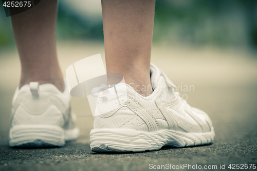 Image of youth sneakers on girl legs on road