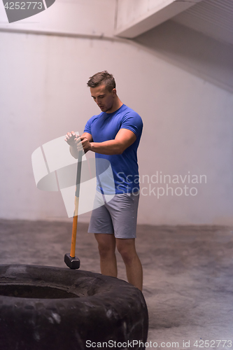 Image of man workout with hammer and tractor tire