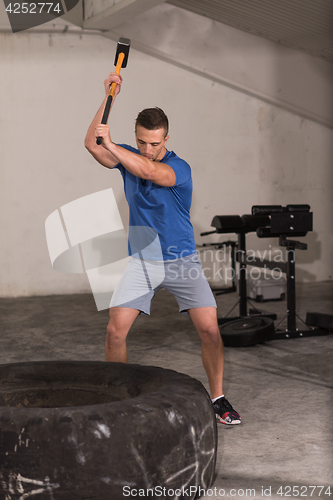 Image of man workout with hammer and tractor tire