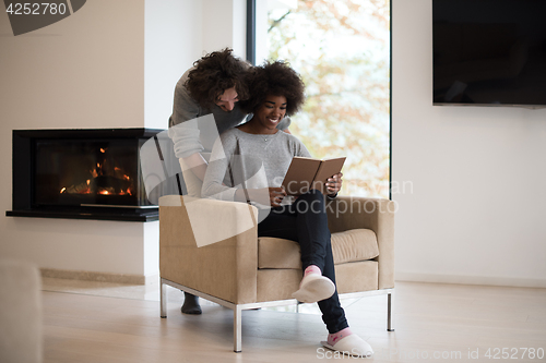 Image of multiethnic couple hugging in front of fireplace