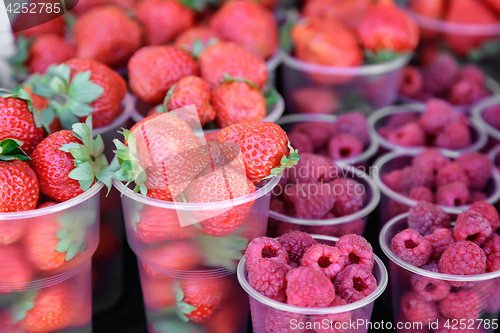 Image of Raspberries and strawberries in containers for sale.