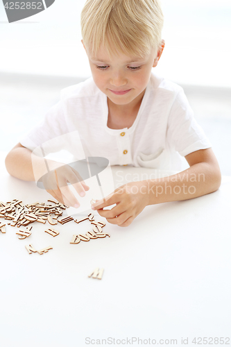 Image of Educational fun, little boy puts puzzle.