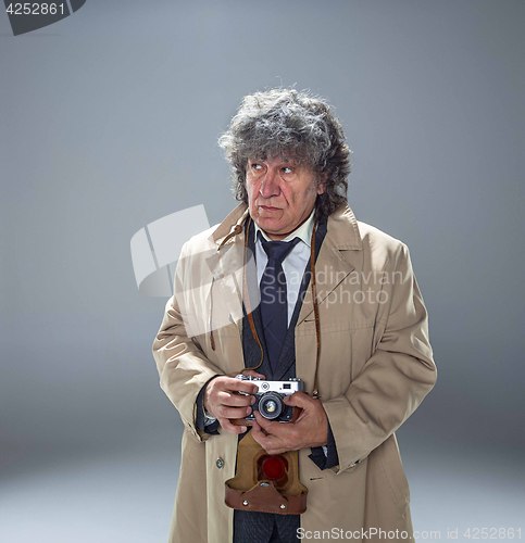 Image of The senior man as detective or boss of mafia on gray studio background