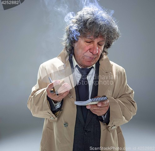 Image of The senior man as detective or boss of mafia on gray studio background