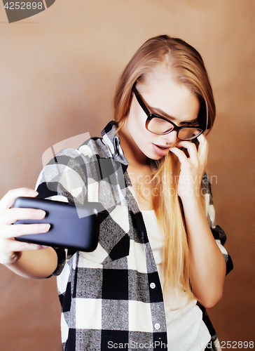 Image of young pretty blond hipster girl making selfie on warm brown back