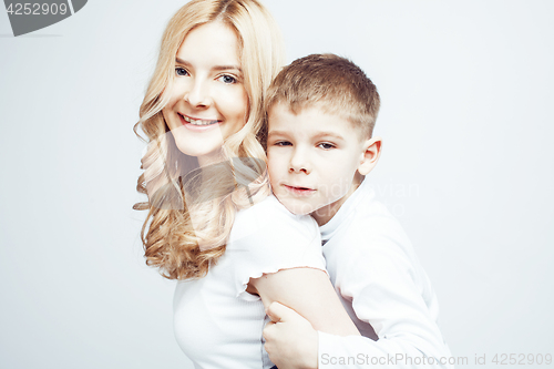 Image of young modern blond curly mother with cute son together happy smiling family posing cheerful on white background, lifestyle people concept, sister and brother friends