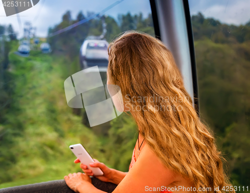 Image of The girl in the cabin cable car in the mountains.