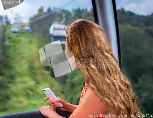 Image of The girl in the cabin cable car in the mountains.