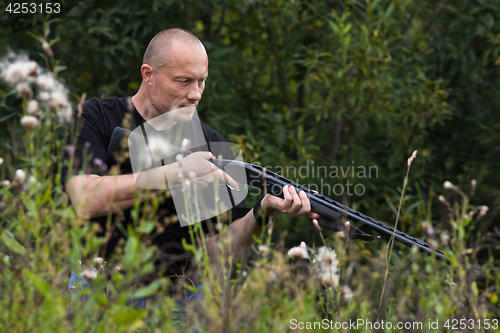 Image of hunter with a gun among the grass