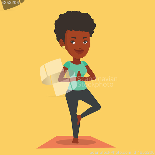Image of Young woman practicing yoga tree pose.