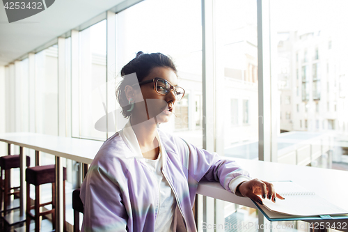 Image of young cute hipster girl student sitting in cafe with notebook re