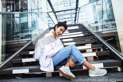 Image of young cute indian girl at university building sitting on stairs 