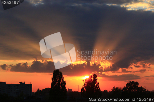 Image of summer sunset with dark sky and sunny beams