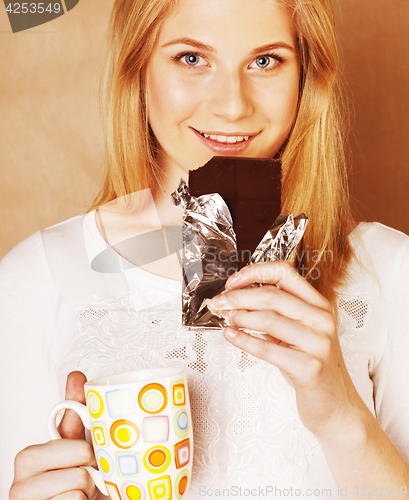 Image of young cute blond girl eating chocolate and drinking coffee close