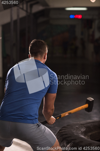 Image of man workout with hammer and tractor tire