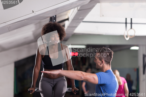 Image of black woman doing parallel bars Exercise with trainer