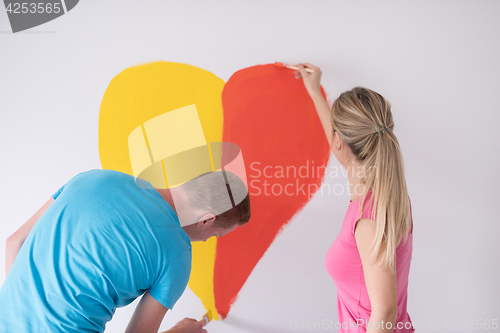 Image of couple are painting a heart on the wall