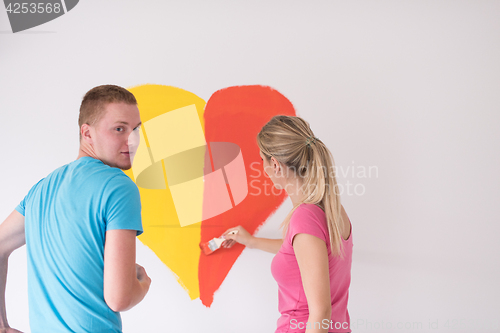 Image of couple are painting a heart on the wall